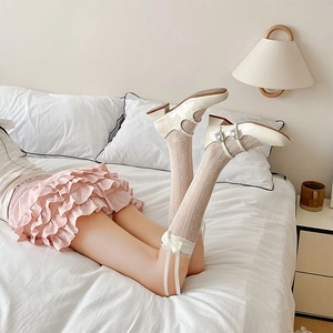 Close-up of heart jacquard lace socks with elegant ribbon bows and cream Mary Jane shoes