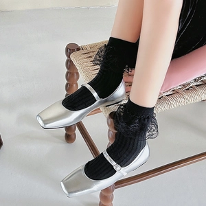 Dettaglio di calze nere a righe verticali con pizzo e scarpe Mary Jane color argento