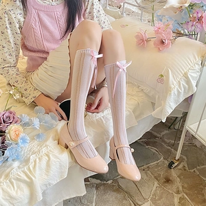 Detail of white hollow lace socks with pink ribbon bows and pearl Mary Jane shoes