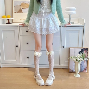 Close-up of white mesh lace socks with silk bow detail and Mary Jane shoes