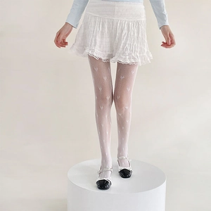Close-up of white heart patterned mesh tights paired with white lace skirt and Mary Janes