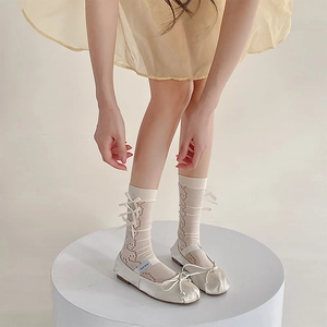 Detailed view of cream silk ballet flats with bow and hollow mesh calf socks