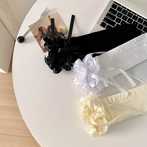 Détail de jambières Lolita en dentelle avec nœuds en noir, blanc et beige