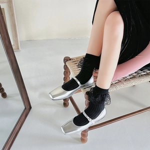 Detail of silver Mary Jane square toe shoes styled with black lace trim socks