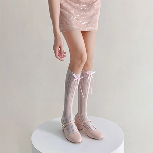Detail of white hollow knit knee-high socks featuring sweet pink silk bows and pearls