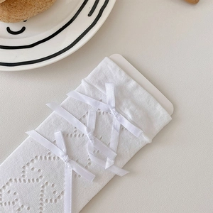 Detailed view of white Lolita socks with mesh hollow-out pattern and silk bows