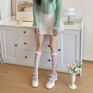 Detail of white lace calf socks with bows paired with Mary Jane heels and short skirt