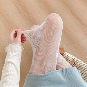Close-up of white heart patterned fishnet tights showing high elasticity and mesh detail