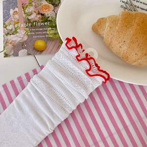 Dettaglio di calze in pizzo floreale bianco con bordi a balze rosse in stile vintage