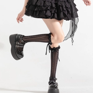 Détail de chaussettes hautes Lolita noires avec dentelle, rubans et motifs ajourés