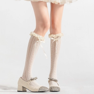 Détail de bas en dentelle blanche avec double volant et nœud en ruban de satin