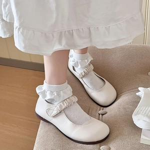 Détail de chaussures Mary Jane blanches avec brides à volants et chaussettes en dentelle