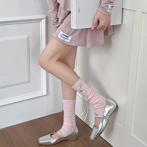 Detailed side view of pink knit leg warmers featuring silver star charms and ribbon ties