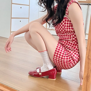 Dettaglio delle scarpe Mary Jane in vernice rossa con calzini in pizzo e base in legno