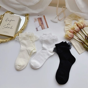 Flat lay of lace trim socks in beige, white, and black with ribbed texture