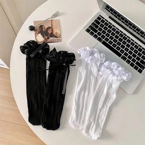 Détail de chaussettes Lolita avec dentelle à volants et nœuds en ruban noir et blanc