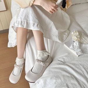 Gros plan de chaussettes en dentelle Lolita blanches avec des ballerines Mary Jane et jupe