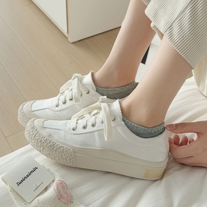 Detail view of white platform canvas sneakers with unique wavy texture on the side