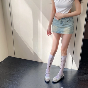 Détail de chaussettes hautes blanches en dentelle avec nœuds noirs et chaussures argentées