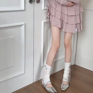 Close-up of pink layered skirt with white knitted leg warmers and silver Mary Janes