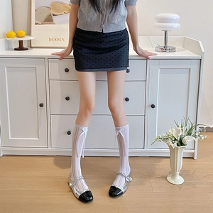 Detail of white hollow lace knee-high socks with cute bow accents and Mary Jane shoes
