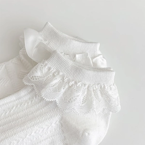 Gros plan de chaussettes Lolita blanches avec dentelle délicate et nœuds en satin