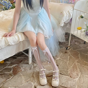 Close-up of white Mary Jane shoes with heart buckles and knit bow knee-high socks