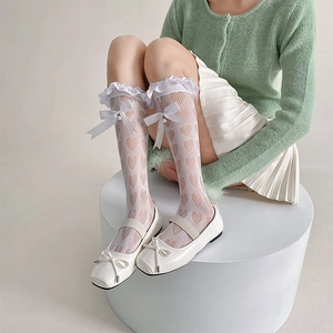 Détail de chaussettes blanches en dentelle à cœurs ajourés avec volants et nœud perlé