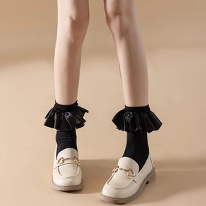 Detail of cream loafers with gold horsebit buckle and black ruffle trim socks