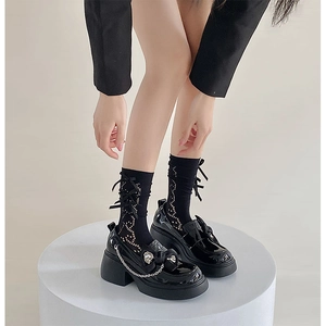 Close-up of black Lolita platform shoes with bow and chain detail on hollow out socks