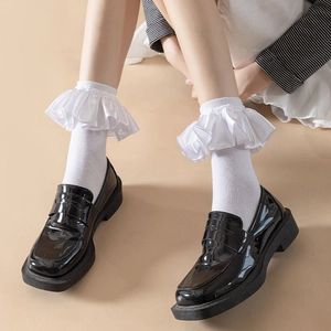 Detailed view of white ruffle socks paired with black patent leather platform loafers