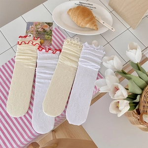 Dettaglio delle calze in pizzo per bambini con trame floreali e bordi a balze curati
