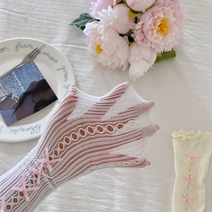 Détail de chaussettes en dentelle ajourée avec nœuds roses sur fond texturé