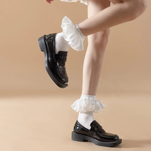 Detail of white ruffle trim ankle socks paired with black patent leather loafers for a JK style