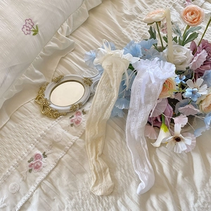 Close-up of white lace mesh socks with bow ribbons and ruffle cuffs in a sweet style