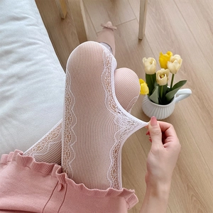 Detail of white lace patterned pantyhose showing stretchability and floral mesh texture