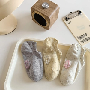 Detailed knit texture of low-cut socks in grey, yellow, and beige with logo patches