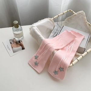 Close-up of pink rib-knit leg warmers with star patches and white ribbon crisscross detail