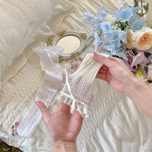 Close-up of white lace mesh leg warmer with sweet ribbon bow and ruffled lace trim
