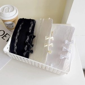 Close-up of three pairs of lace socks with bow accents in white, beige and black colors