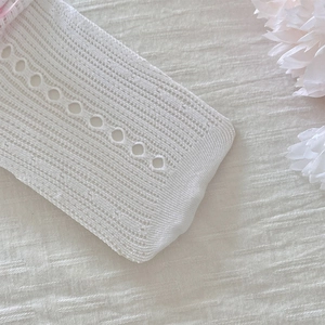 Gros plan de chaussettes en dentelle blanche avec motifs ajourés et nœuds délicats