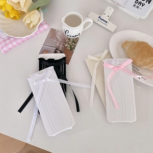 Flat lay of Japanese Lolita calf socks with ribbon bows and hollow knit patterns