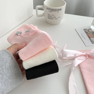 Detail of sweet pink leg warmers with silver star patches and satin ribbons for girls