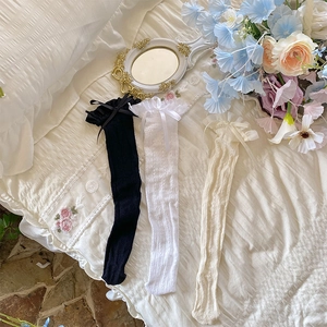 Detail of three sheer lace socks in white, black, and beige with silk bow accents