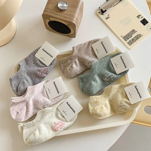 Detailed set of six pastel low-cut cotton socks with embroidered logos on a white tray