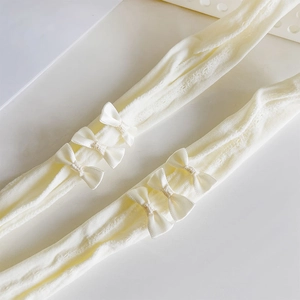 Macro shot of cream white knit tights with delicate satin bows on the side