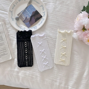 Détail des chaussettes en maille ajourée avec bordure en dentelle et cinq nœuds