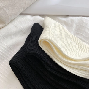 Nahaufnahme der gerippten Socken in Schwarz und Offwhite auf weichem Stoffhintergrund