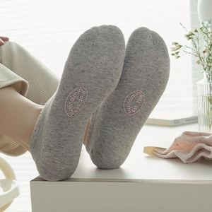 Detailed view of grey low-cut cotton socks featuring pink embroidered logo on the sole