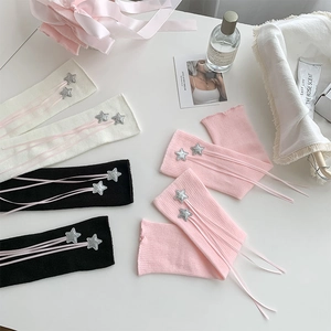 Close-up of knit leg warmers with silver star sequins and pink ribbon bow details